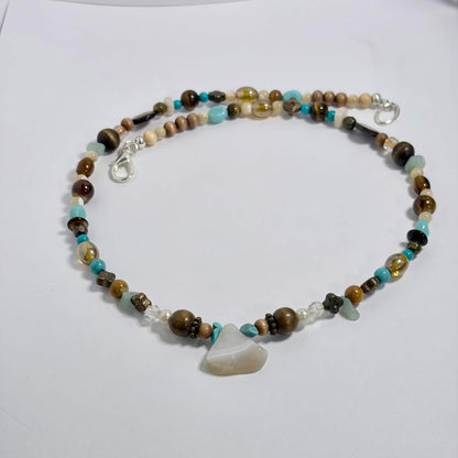 A beaded necklace with a central agate and turquoise stone, featuring brown, beige, and light blue beads, displayed on a white surface.