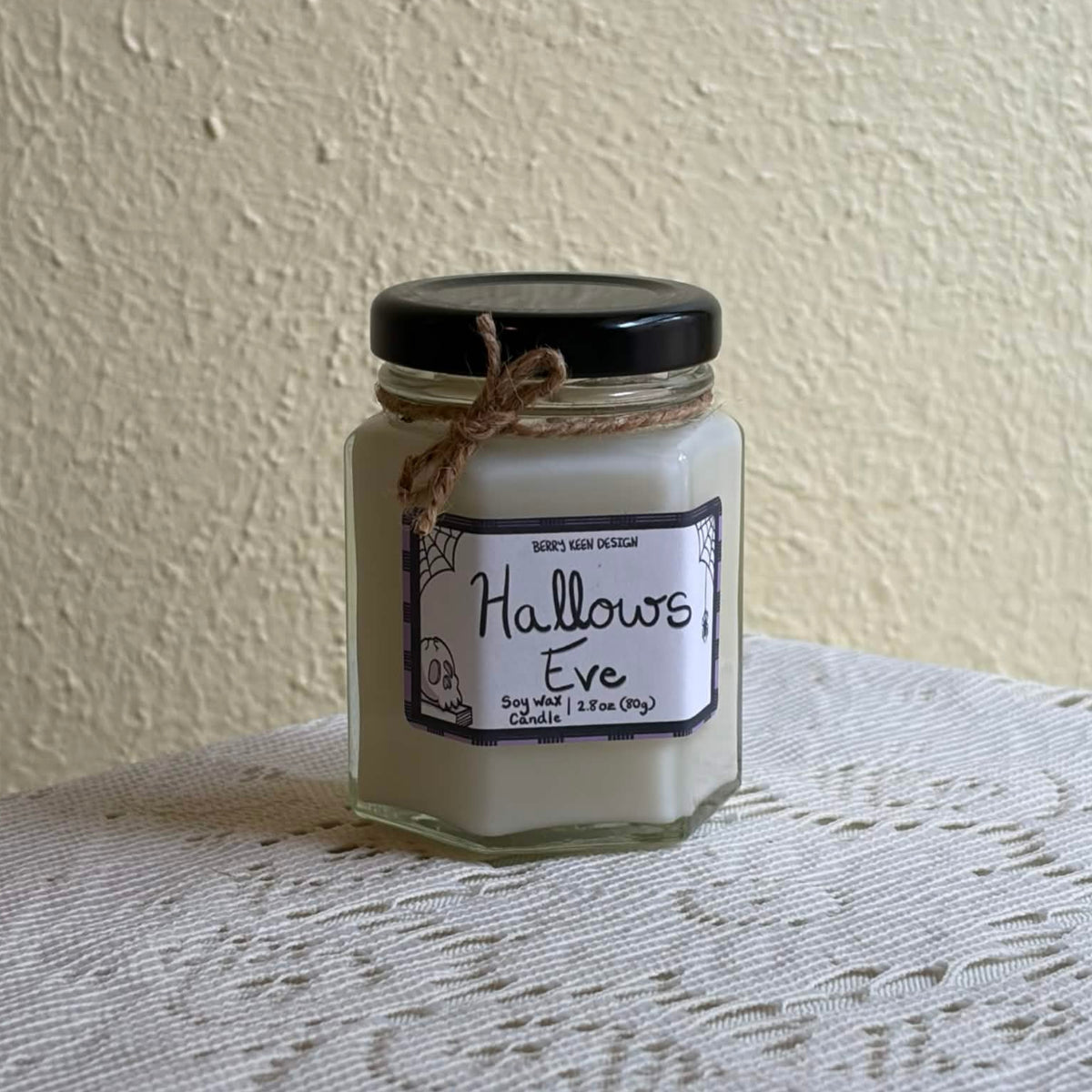 Hallows Eve 2.8oz candle on a lace table cloth