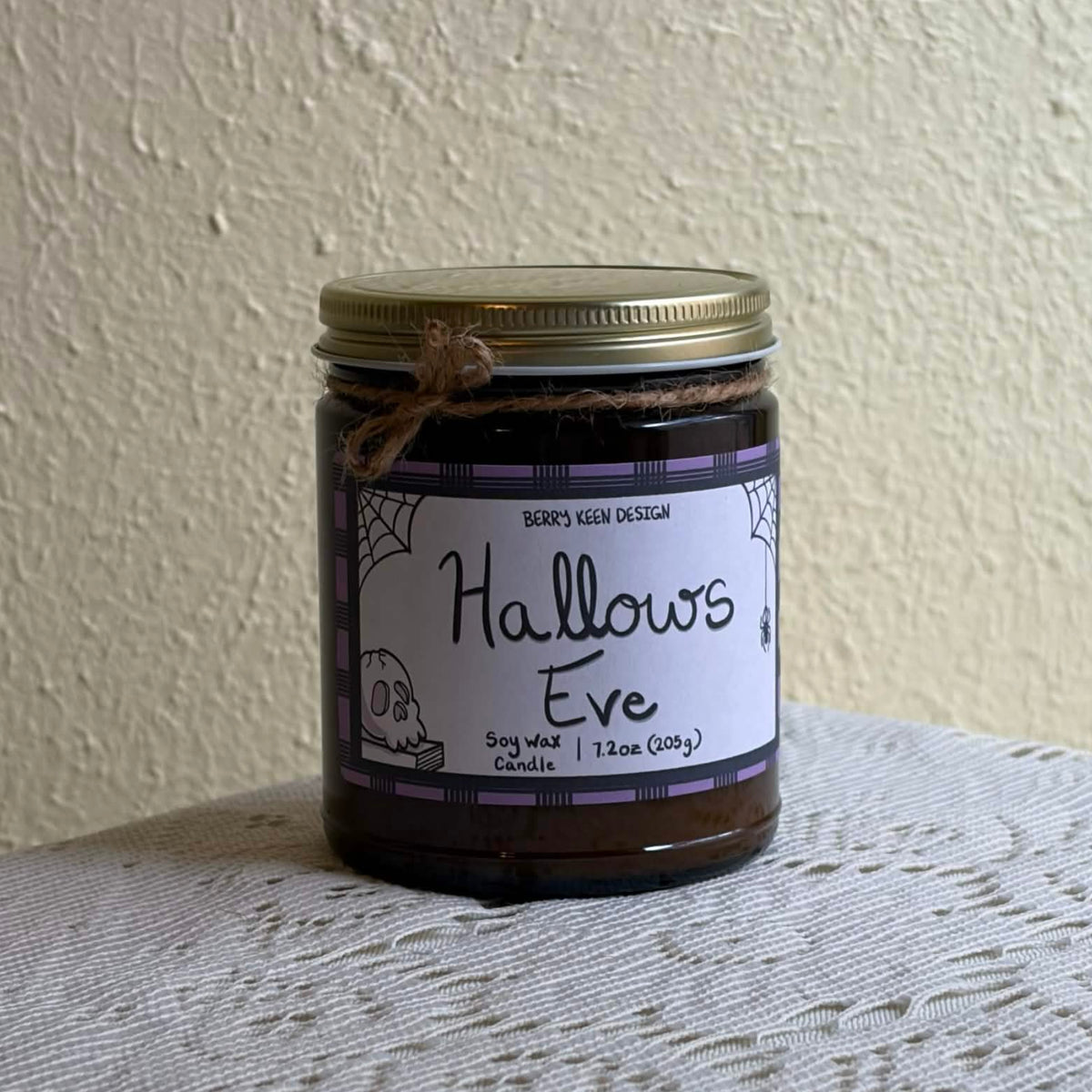 Hallows Eve 7.2oz candle on a lace table cloth