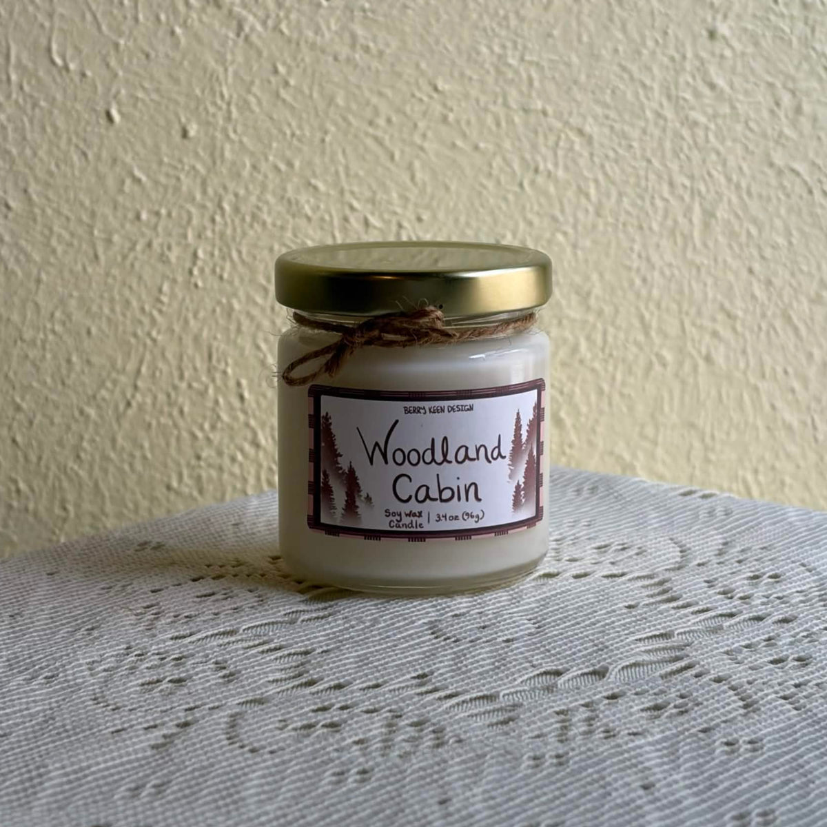 Woodland Cabin 3.4oz candle on a lace table cloth