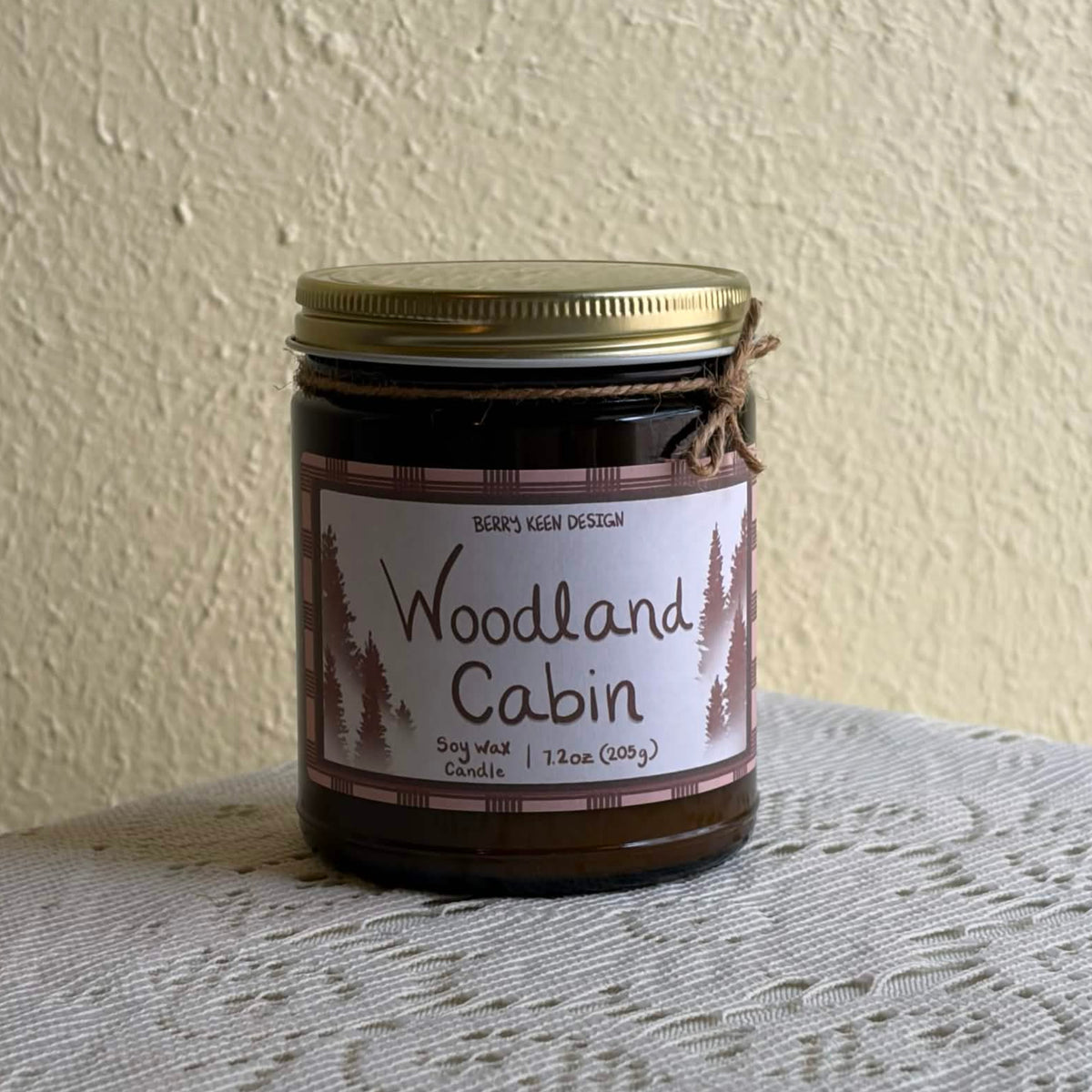 Woodland Cabin 7.2oz candle on a lace table cloth