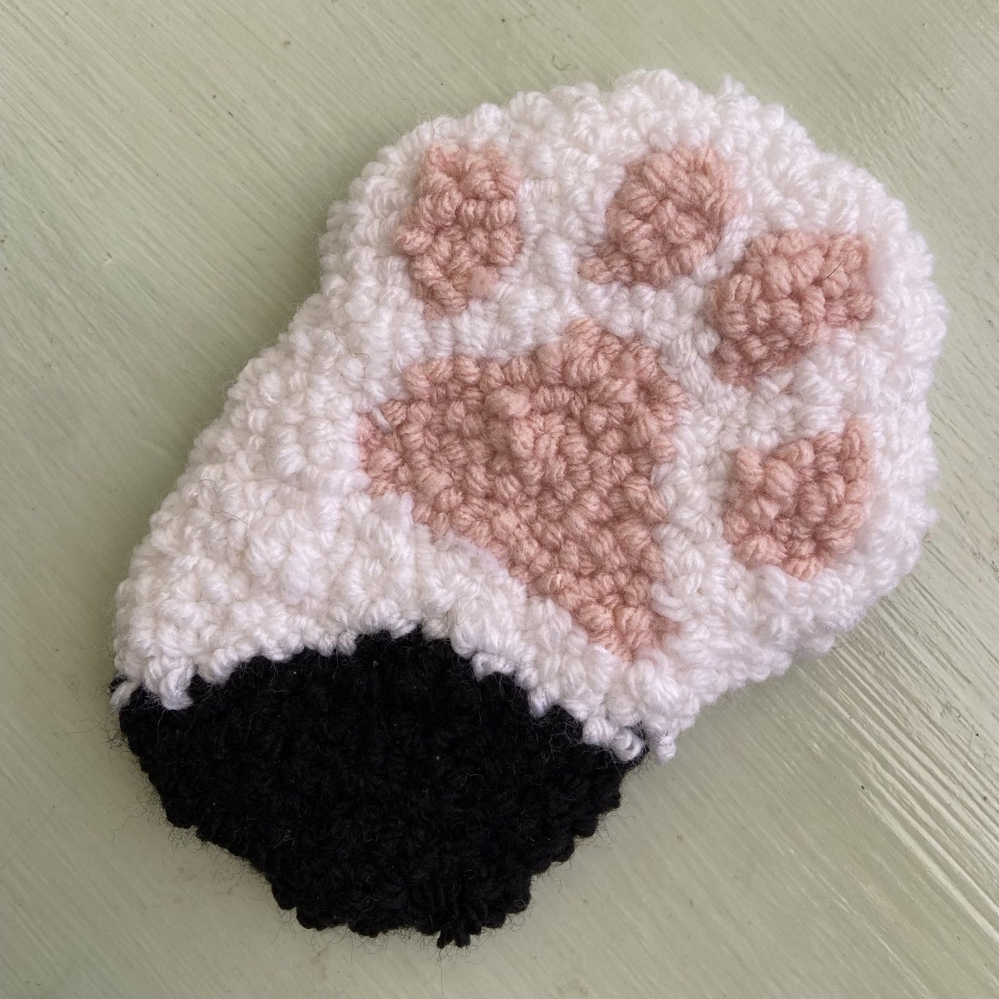 Punch needle paw coaster made with acrylic yarn black/white.