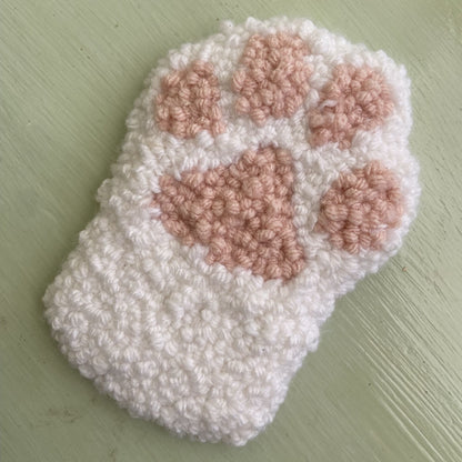 Punch needle paw coaster on a light green background